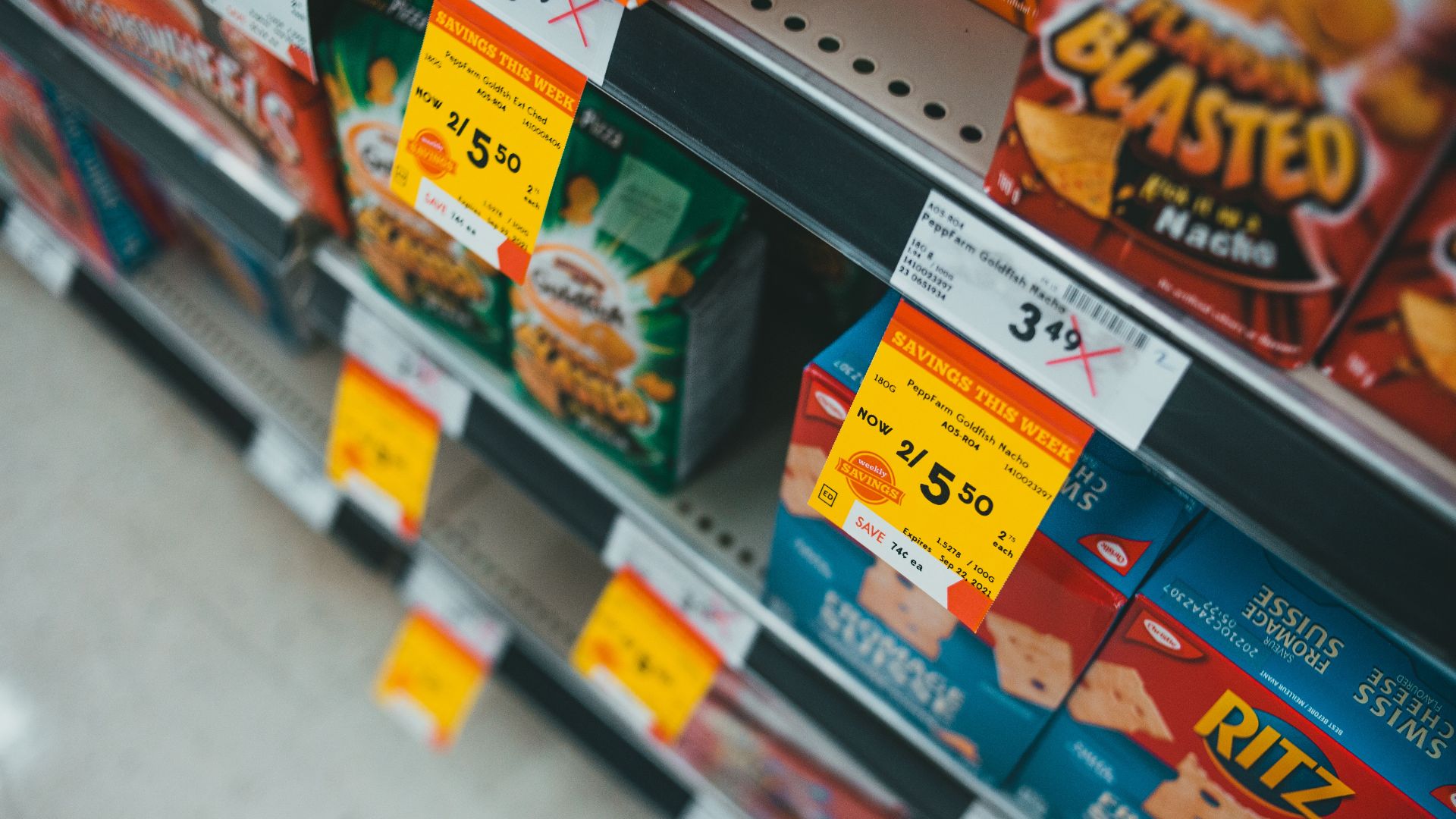Supermarket aisle featuring discounted snacks with visible sale tags and prices.