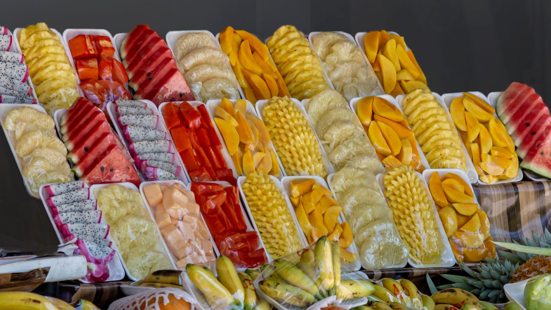 Variety of fresh fruits neatly packed and displayed at a vibrant market stall.