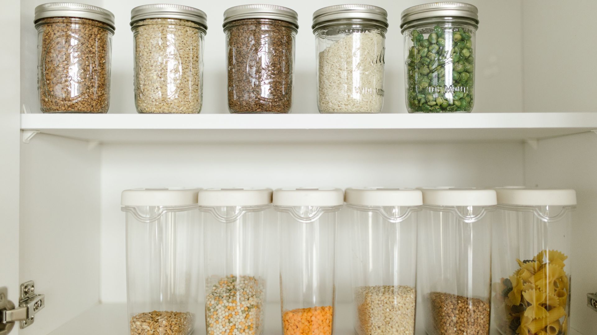 Neatly arranged pantry showcasing grains in glass jars and dry goods in plastic containers.
