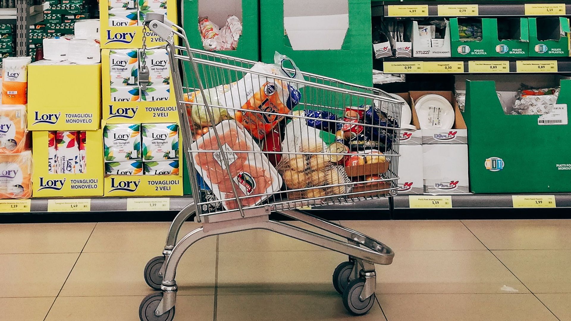 Shopping cart in a vibrant supermarket aisle in Padova, Italy.