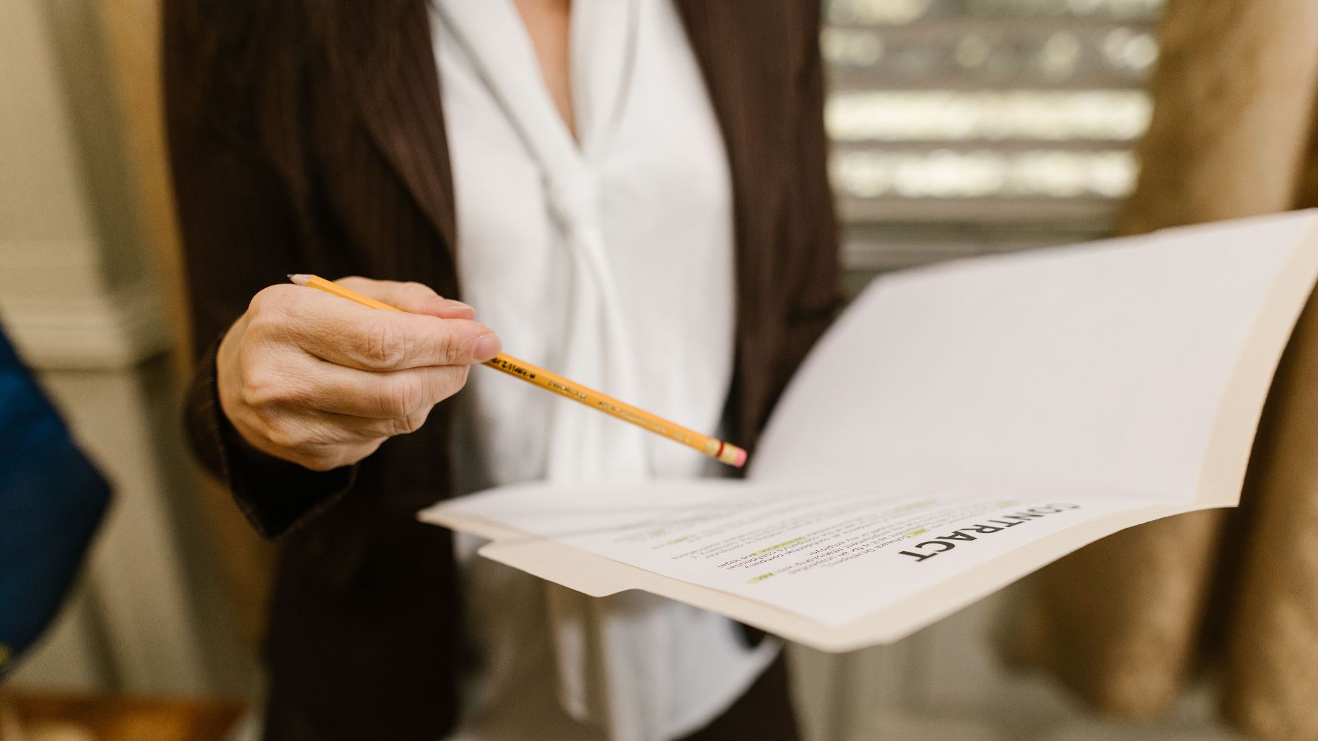 A businesswoman holds a contract, pointing with a pencil. Legal and corporate setting.