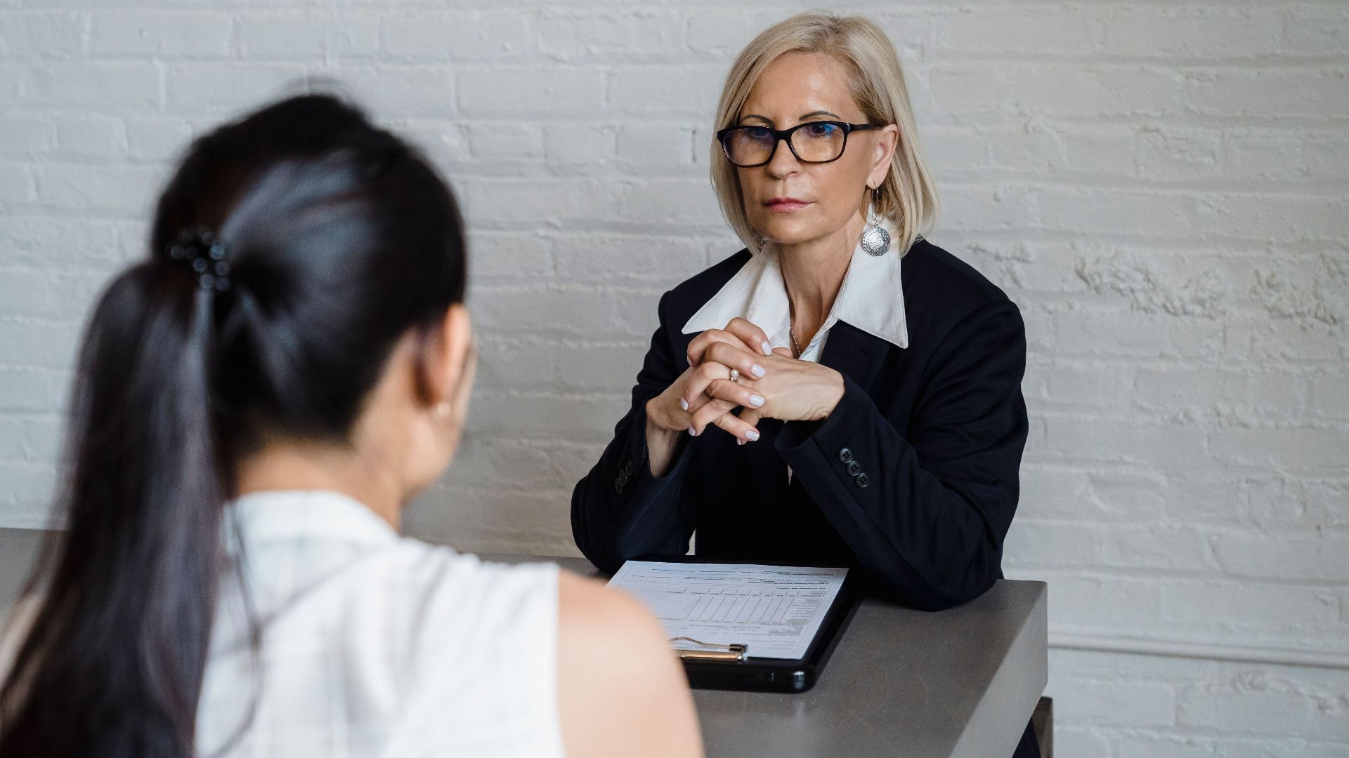 Professional businesswoman in a black blazer conducting an interview indoors.