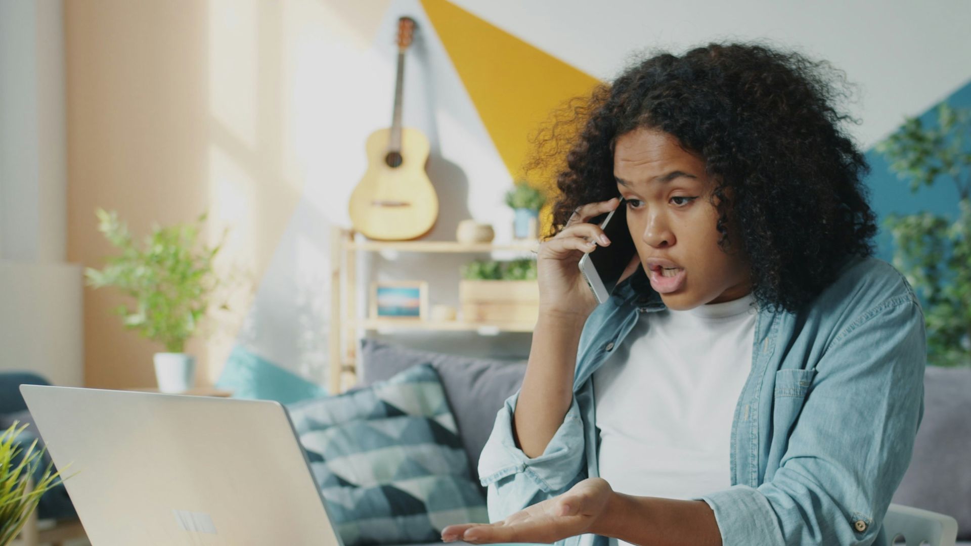 Young woman talking on phone at laptop desk