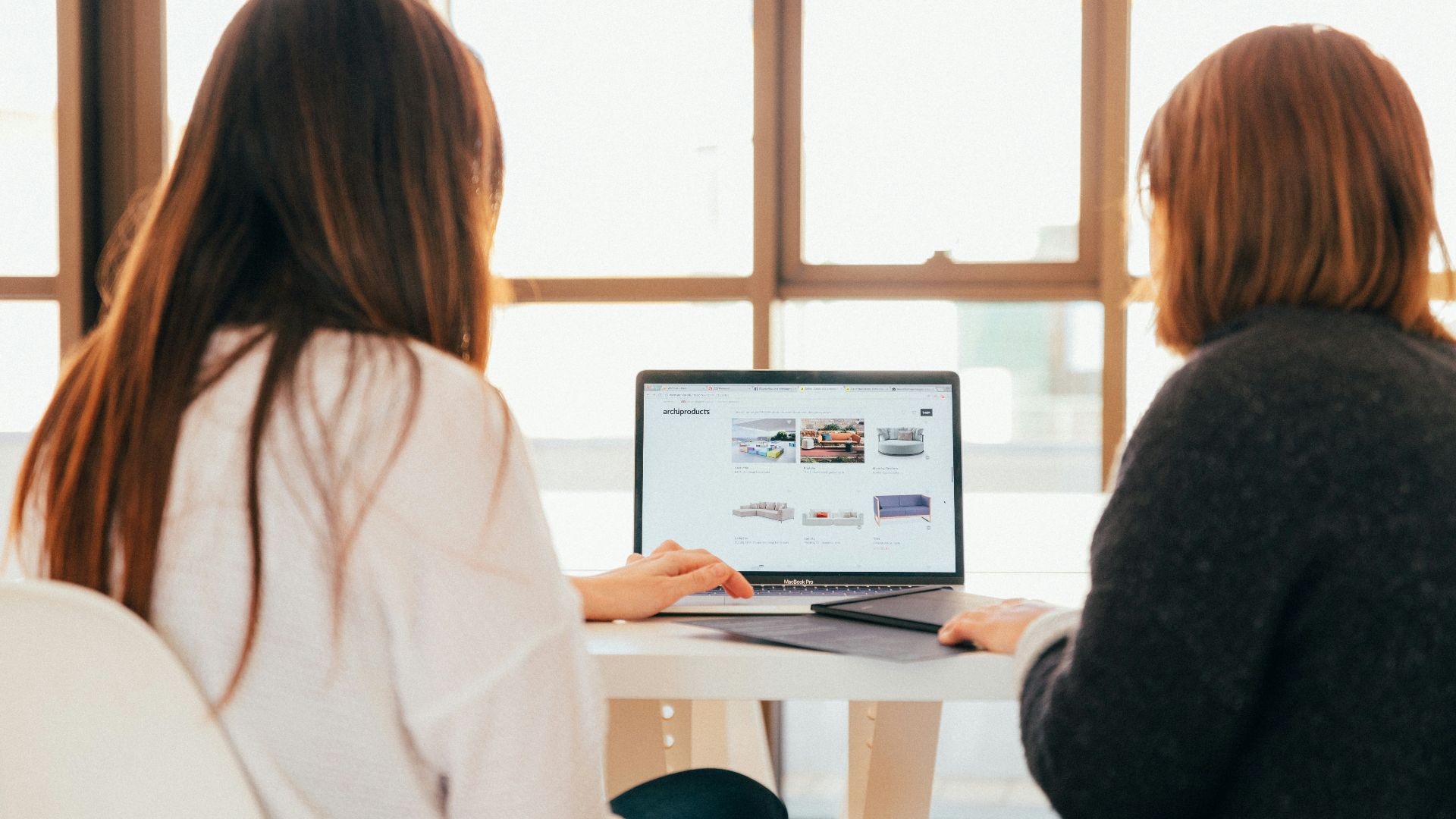 two women talking while looking at laptop computer