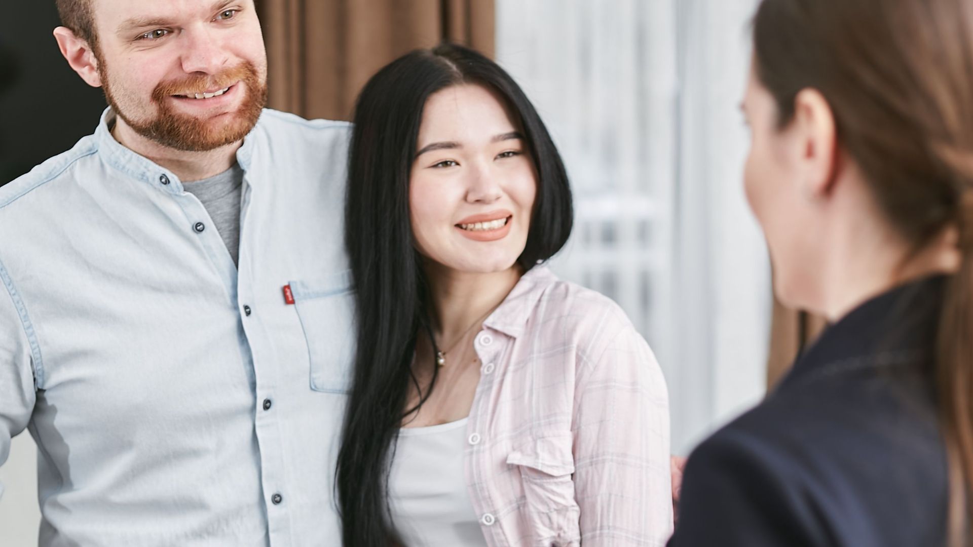 Smiling interracial couple engaging with a professional advisor in an indoor setting.