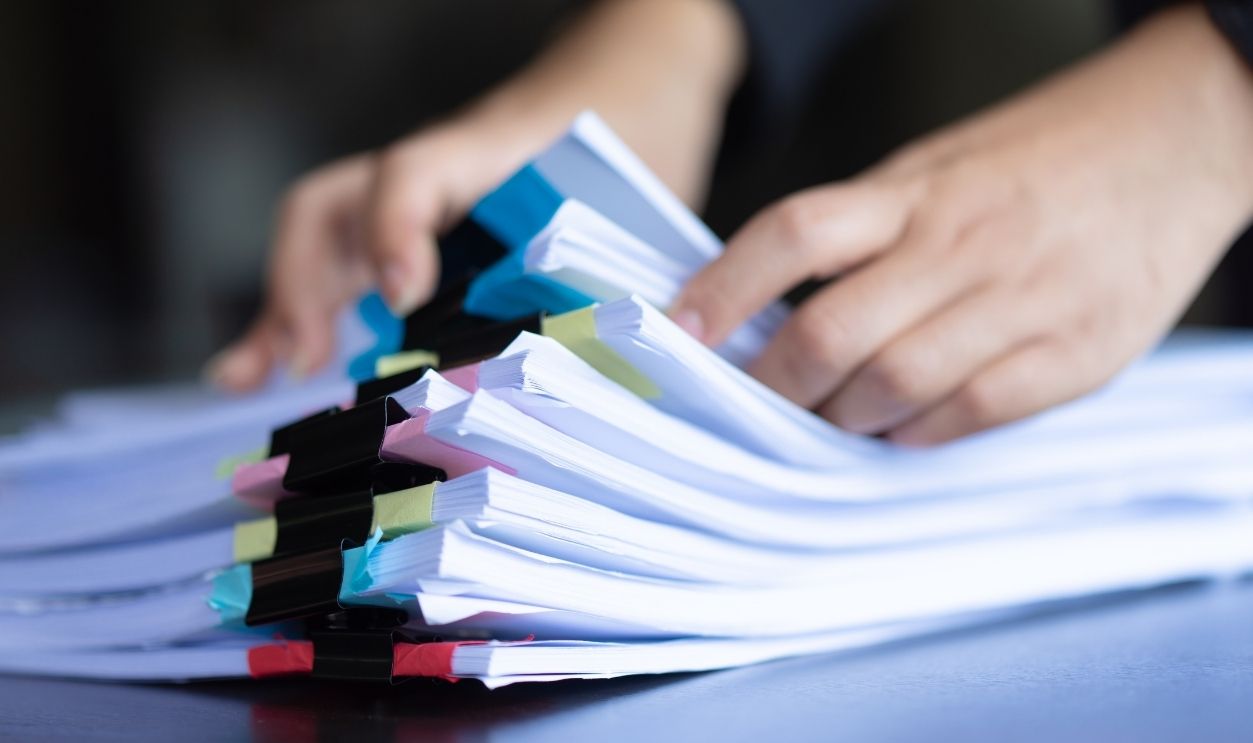 Asian businesswoman standing at her workplace and checking financial documents.