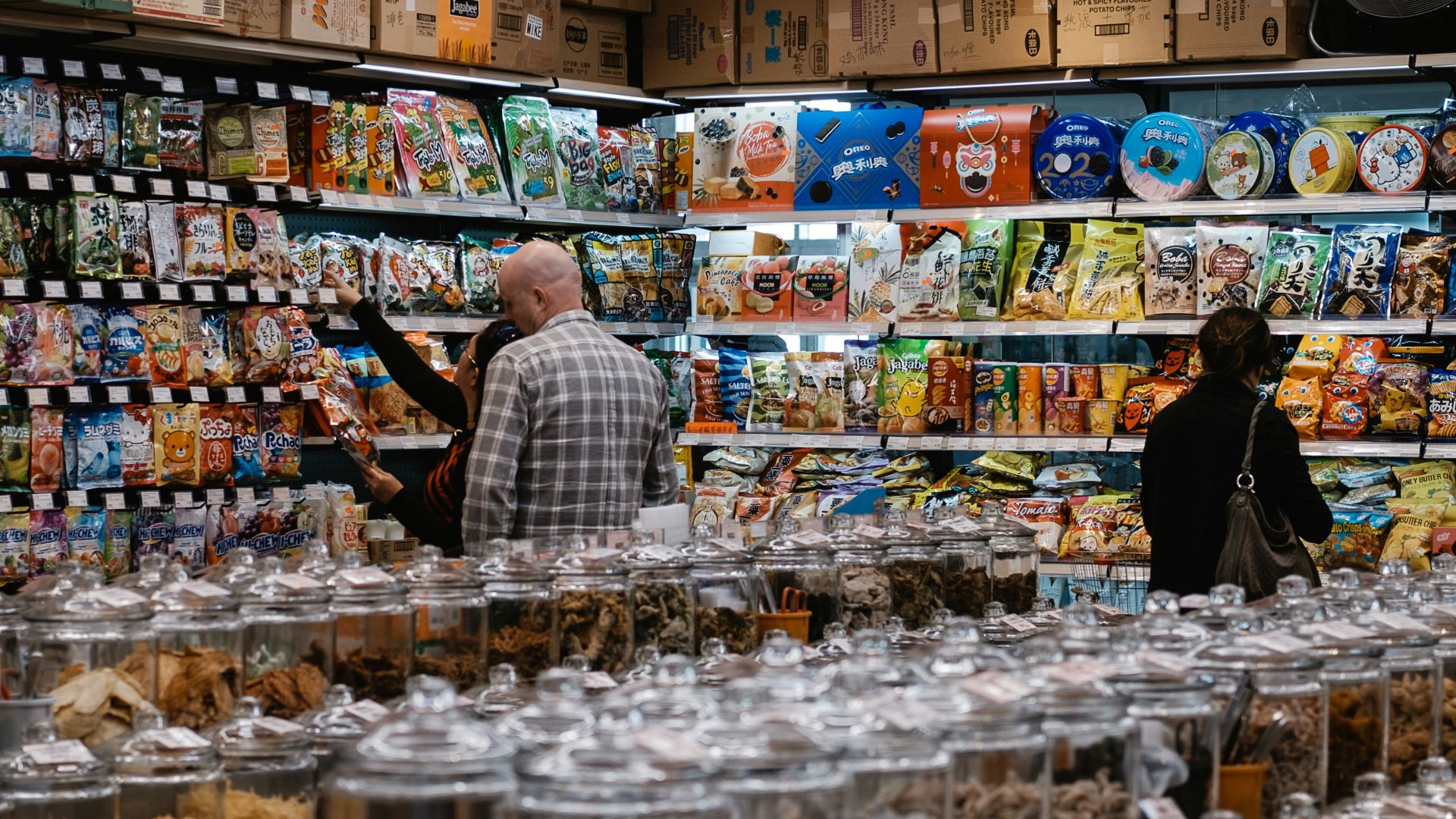 man in blue and white plaid dress shirt standing in front of food display