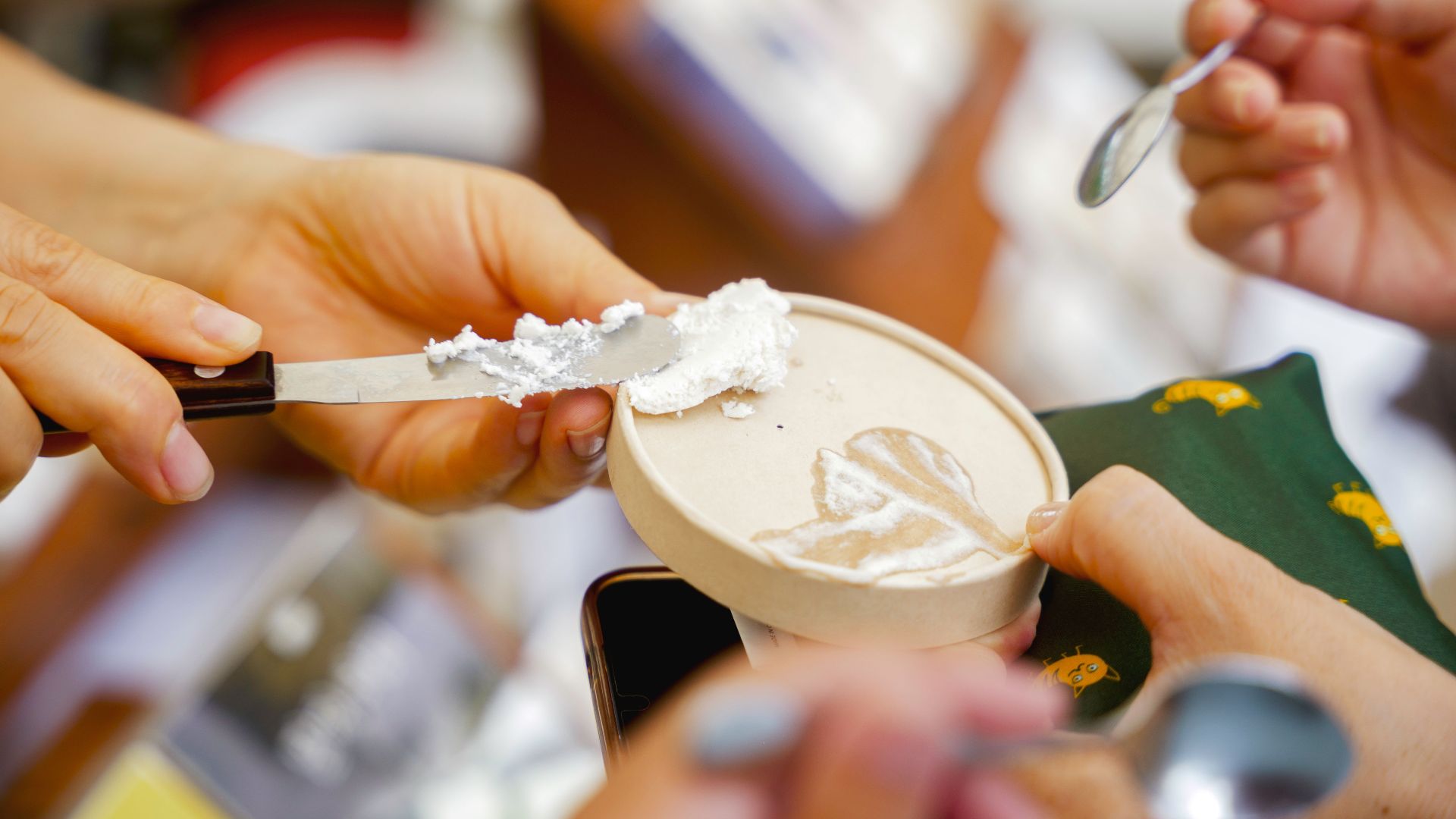 Friends enjoy ice cream together with spoons and knife, highlighting community and fun.