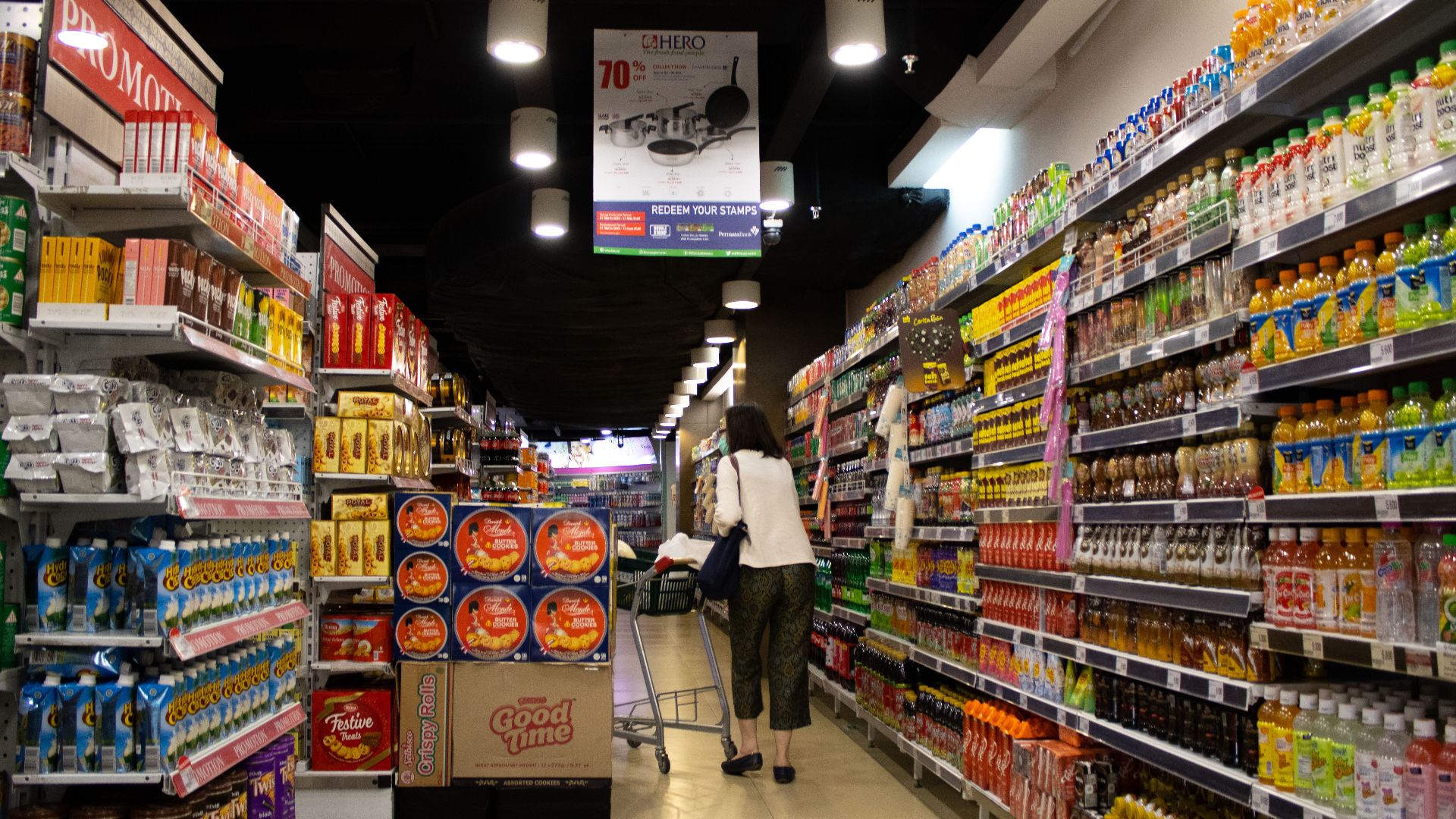 Vibrant supermarket aisle scene with a shopper in Jawa Timur, Indonesia.