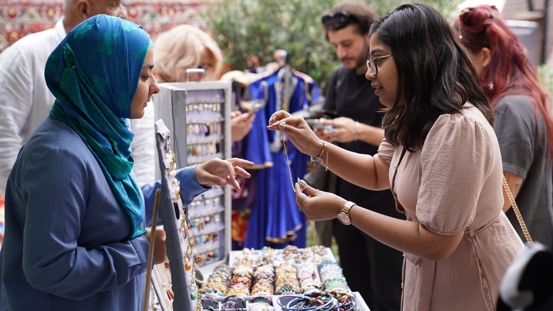 Women engaging in vibrant jewelry trading at an outdoor market, capturing cultural interaction.