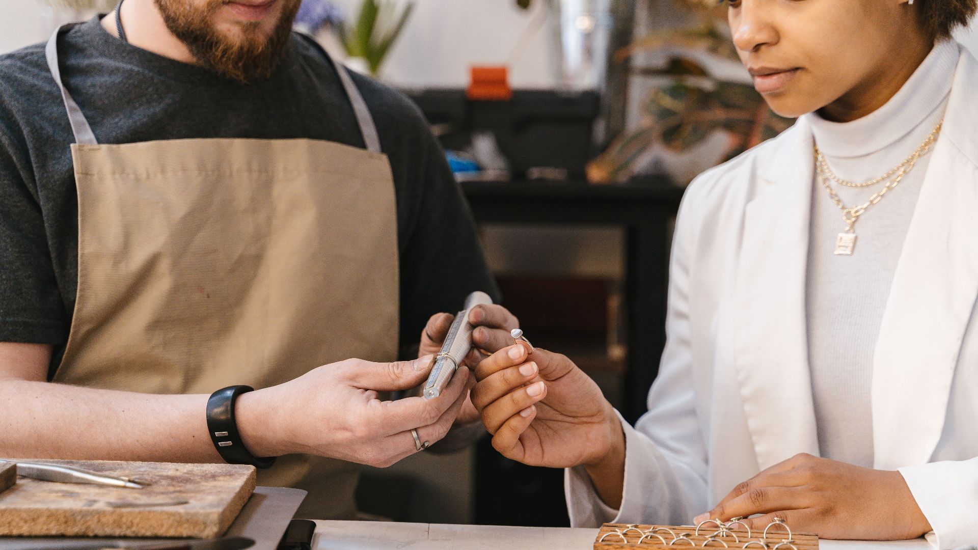 Two artisans collaborate in a workshop, focusing on jewelry design and craftsmanship.