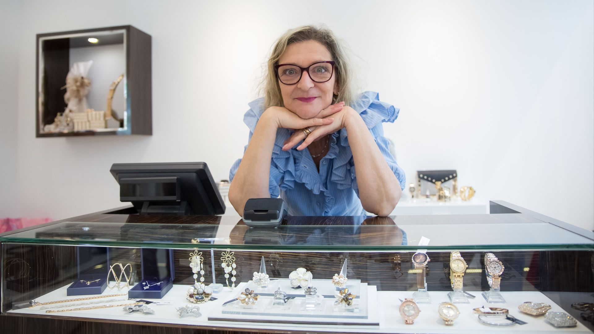 Elegant woman showcasing luxury watches and jewelry in a modern store.