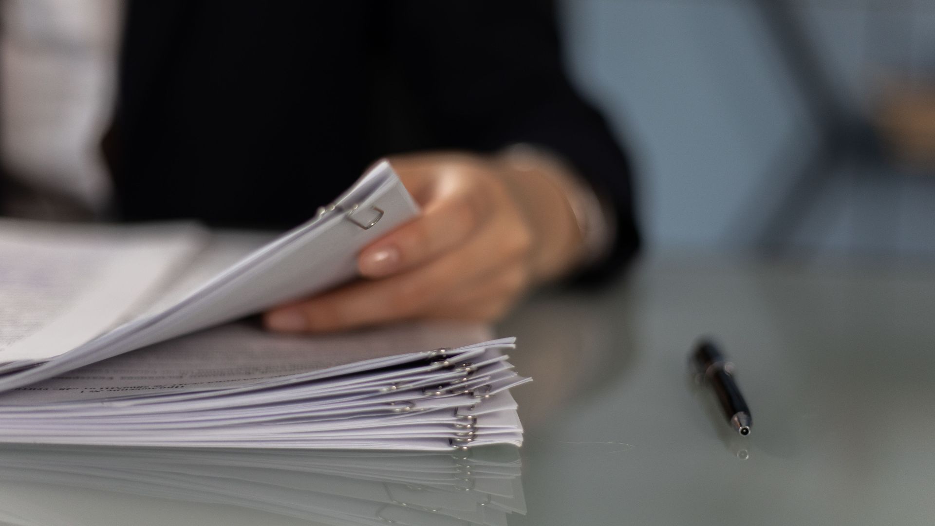 Close-up of a professional organizing a stack of documents on a desk.