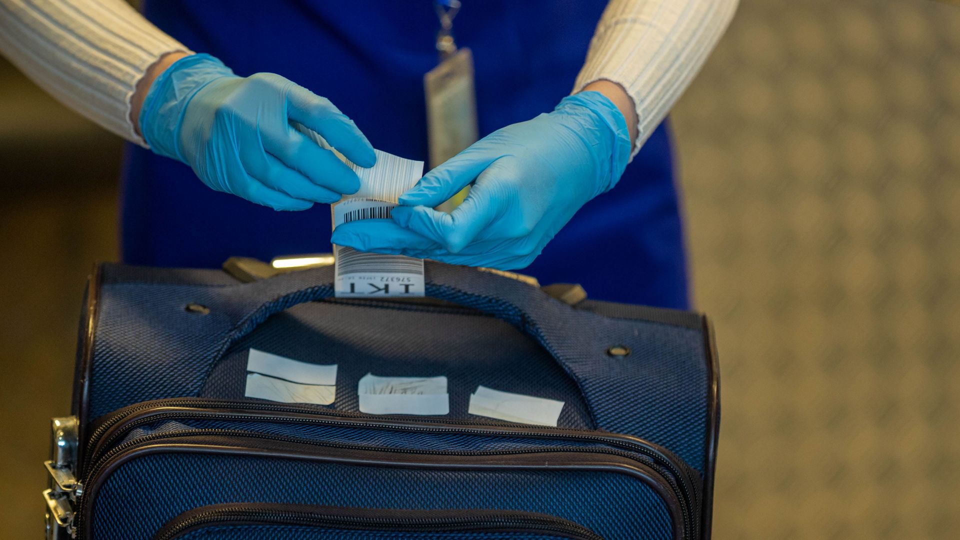 Close-up of airport security process with gloved hands inspecting luggage tags.