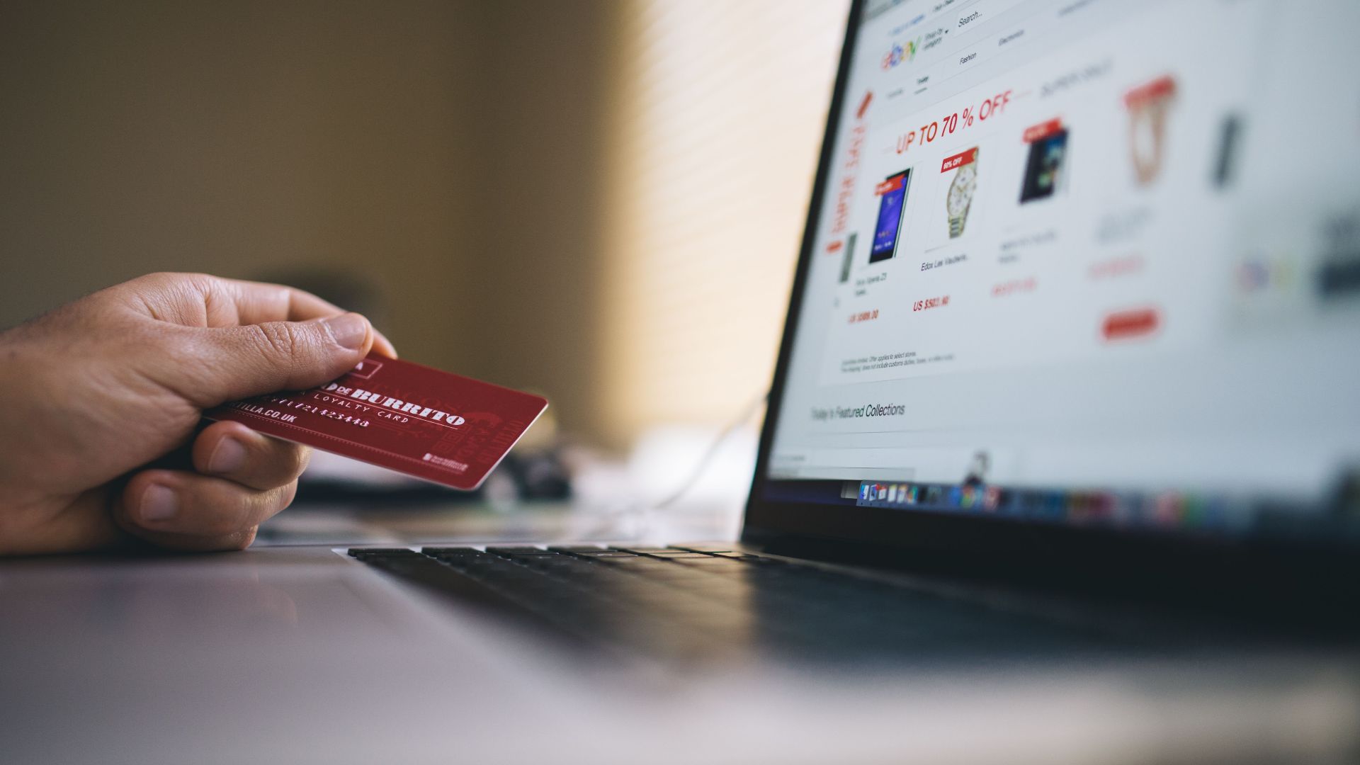 Person holding a credit card while shopping online on a laptop, indicating ecommerce transactions.