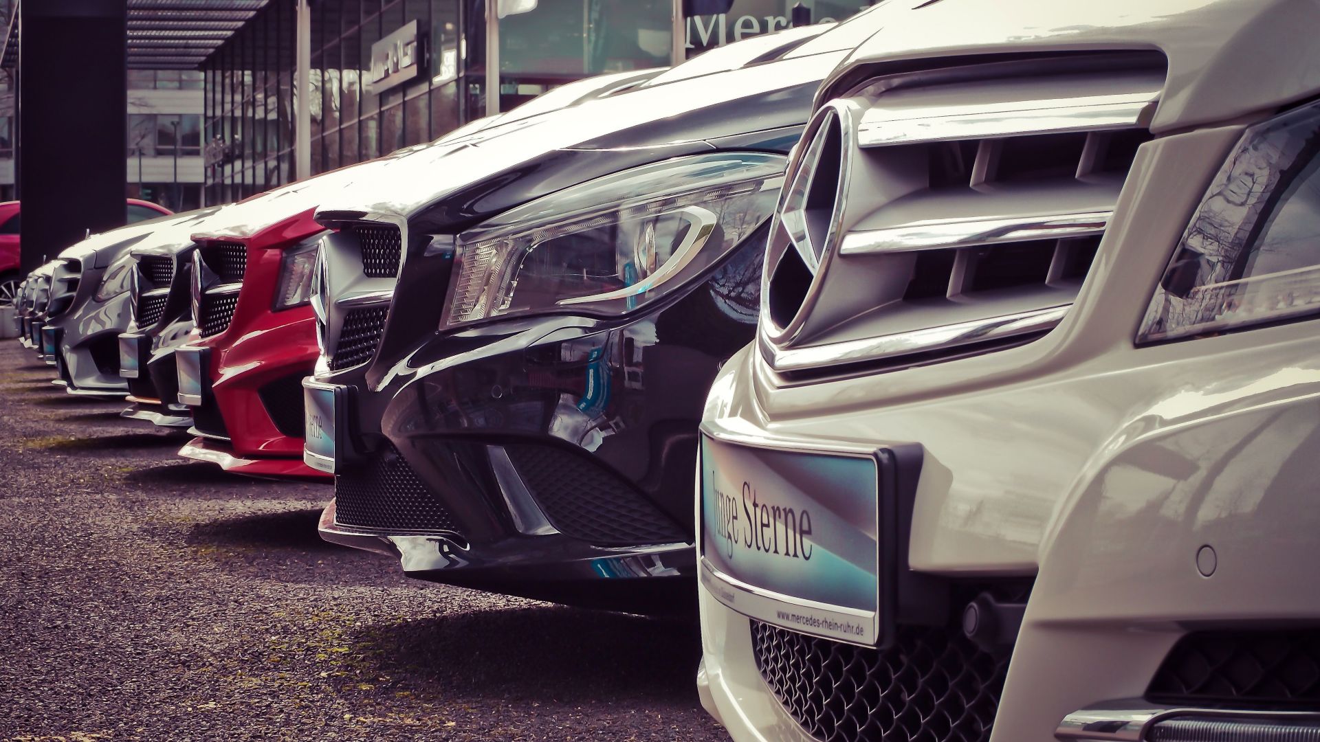 Luxury cars lined up at an outdoor dealership, showcasing sleek designs.
