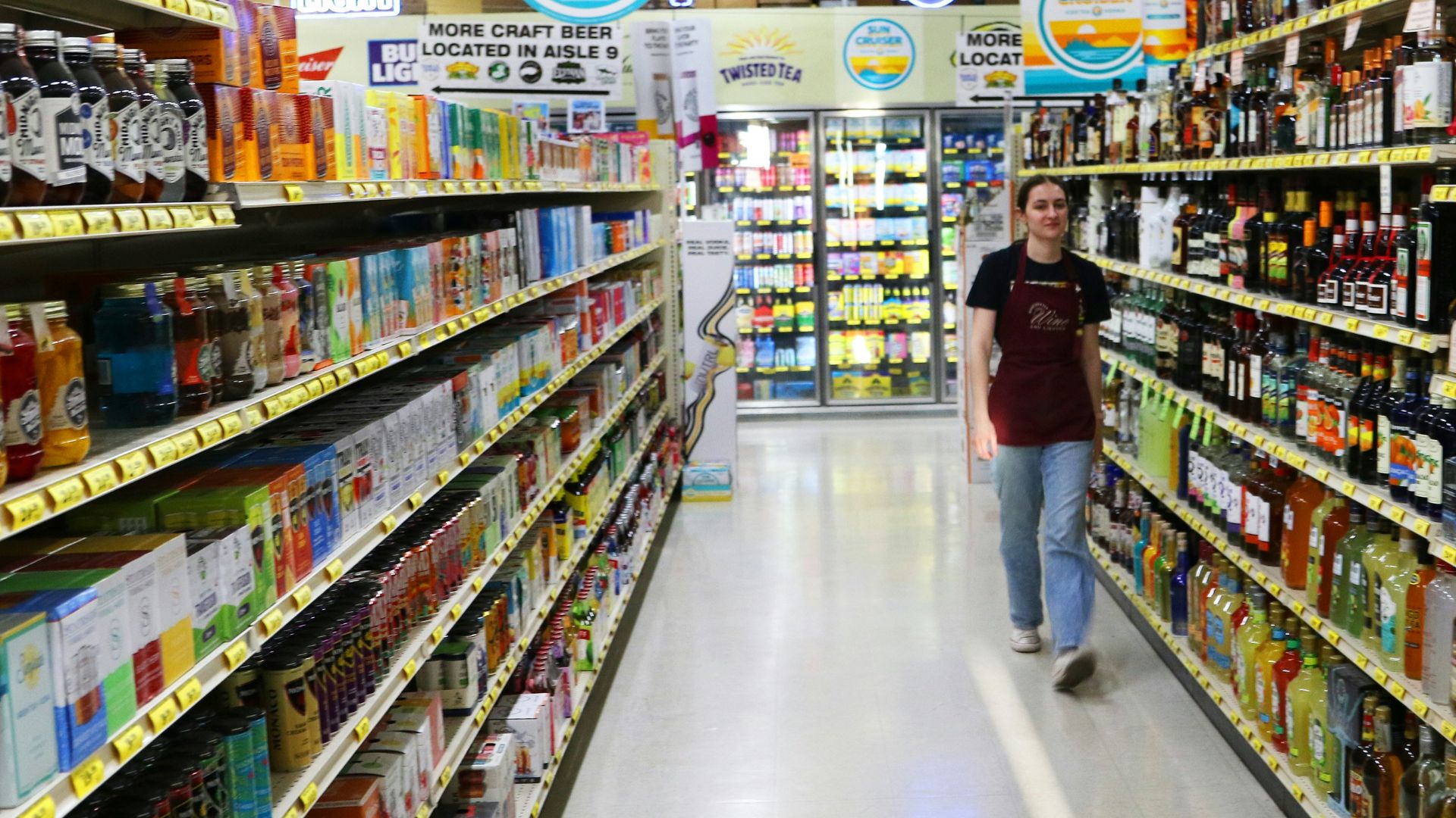 A person walks down a brightly lit grocery store aisle.