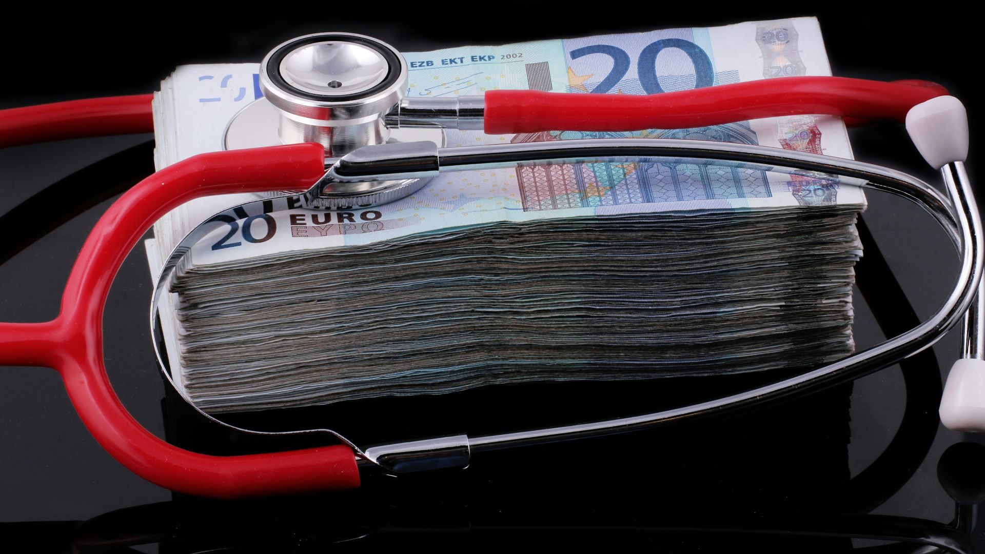 a medical stethoscope resting on a stack of money