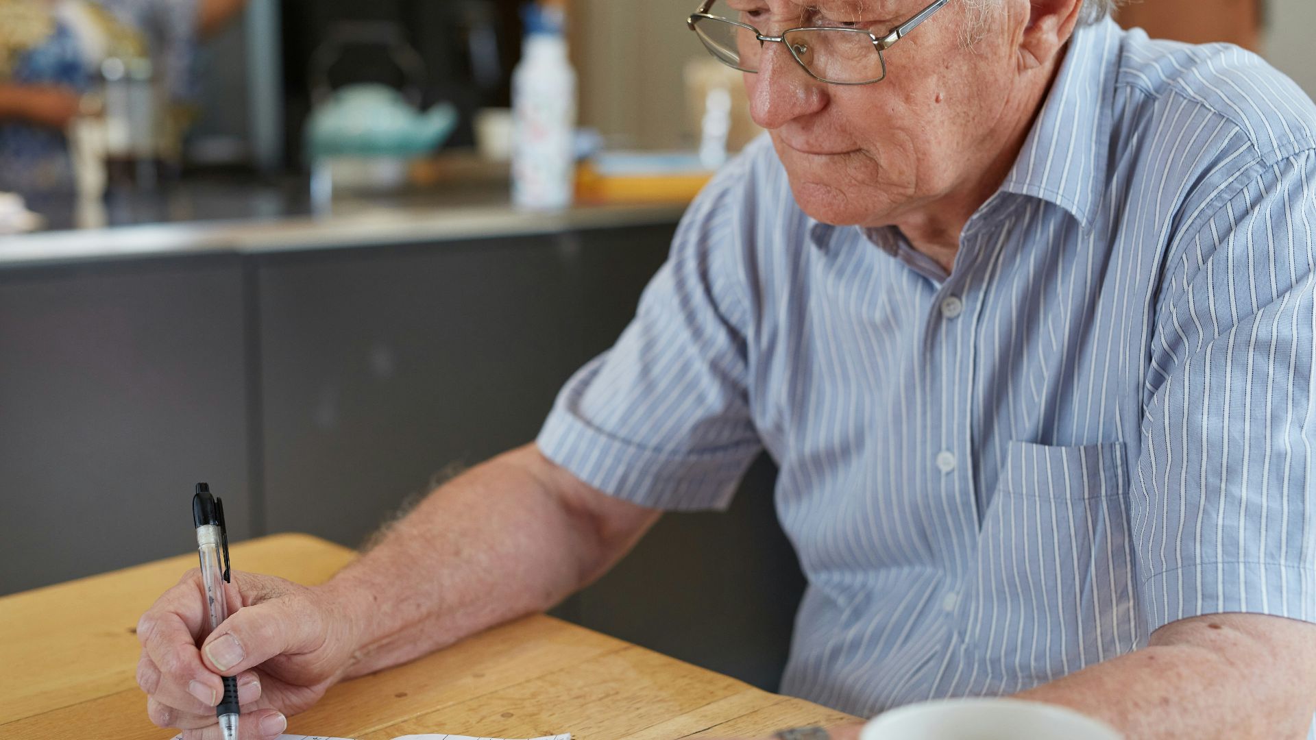 a man sitting at a table writing on a piece of paper