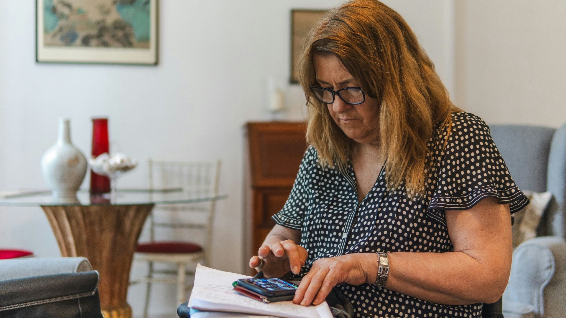 Woman using calculator with papers on table