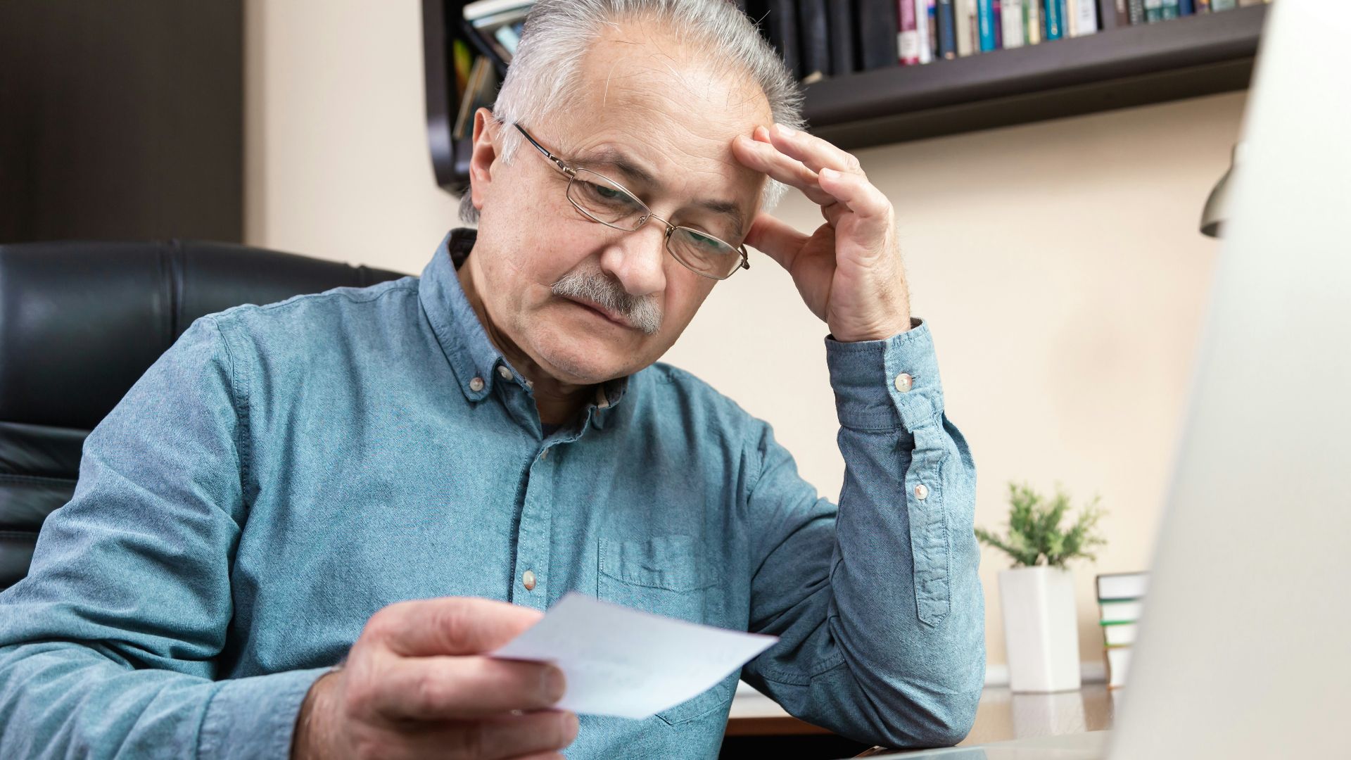 a man holding a pen and looking at a laptop