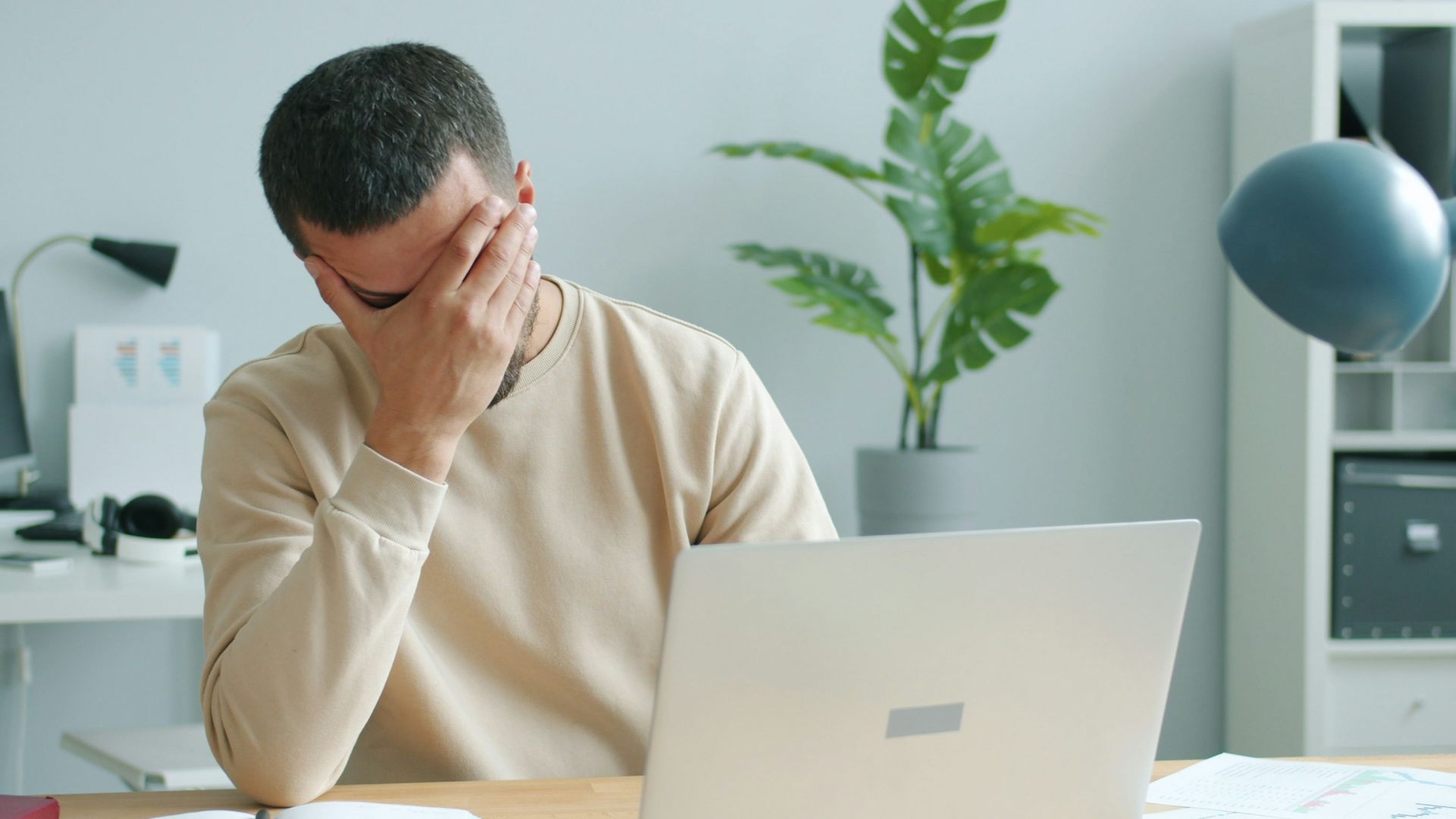Man rubbing his face in front of laptop