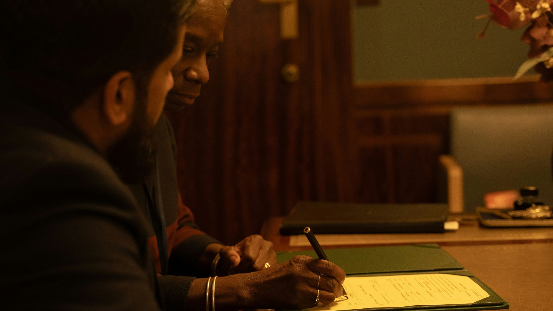 Two people are signing a document at a desk
