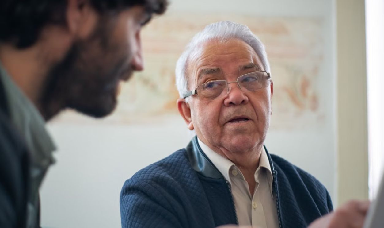 Elderly man with eyeglasses in a thoughtful discussion in Portugal indoors.