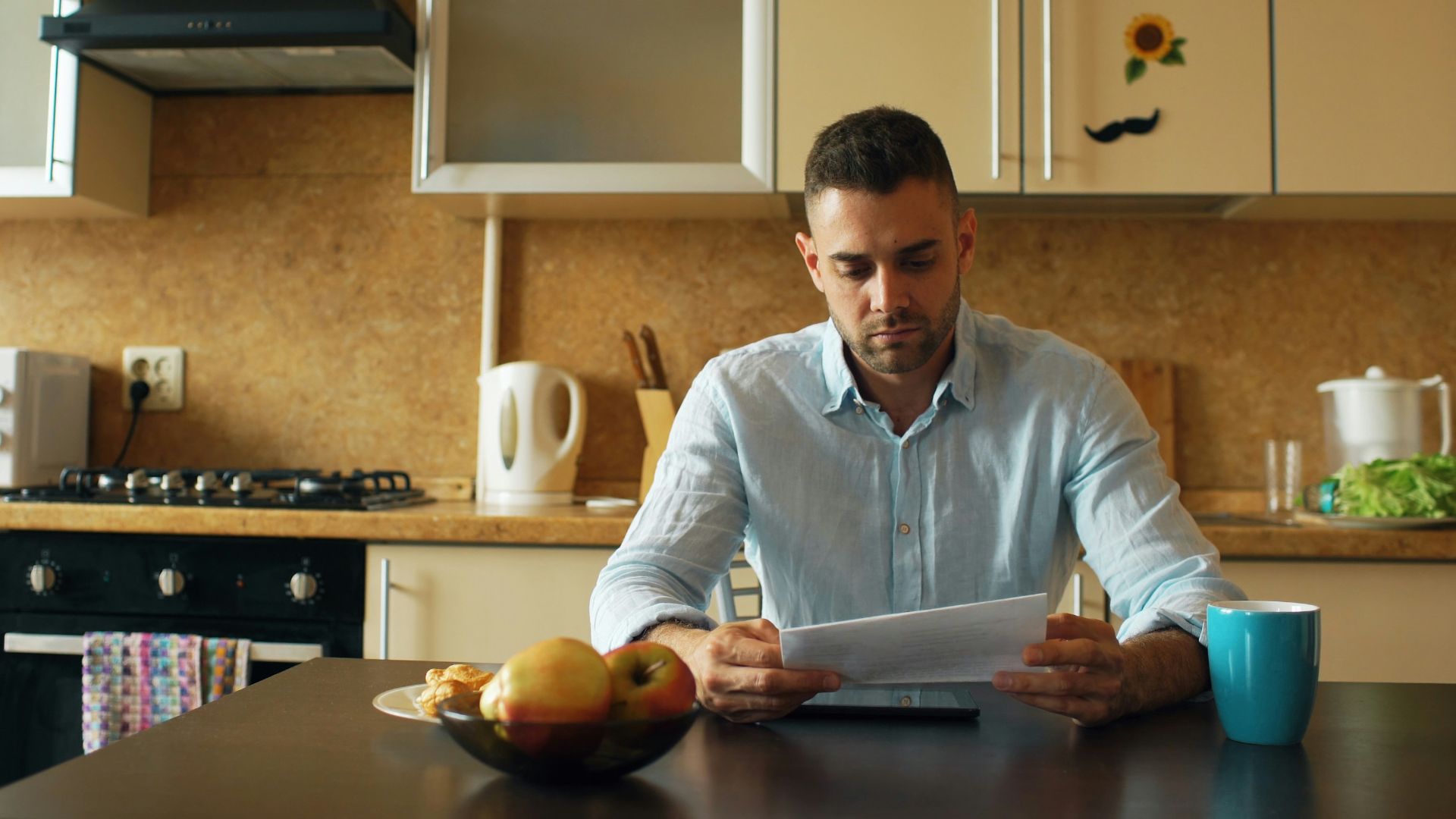 Man reading document at kitchen table with coffee