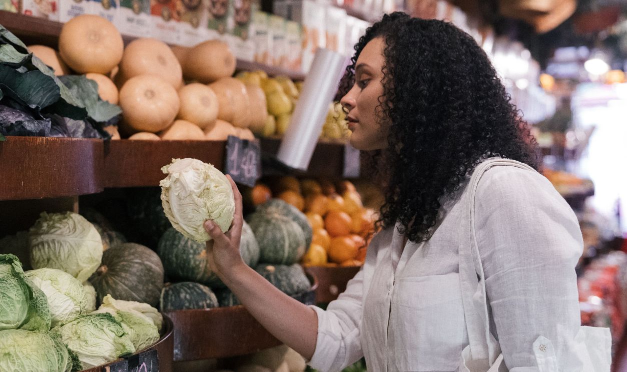 A woman in a white shirt selects fresh cabbage