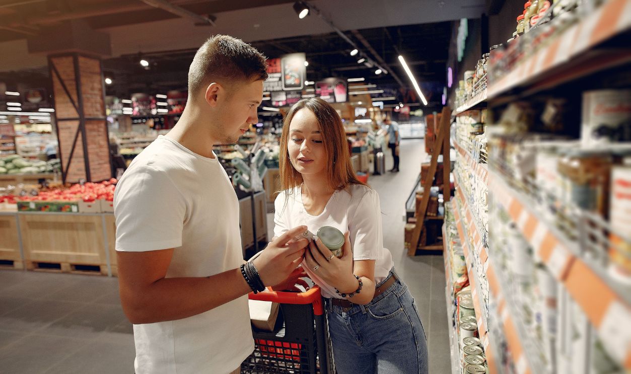 A young couple looking at canned goods in a supermarket aisle