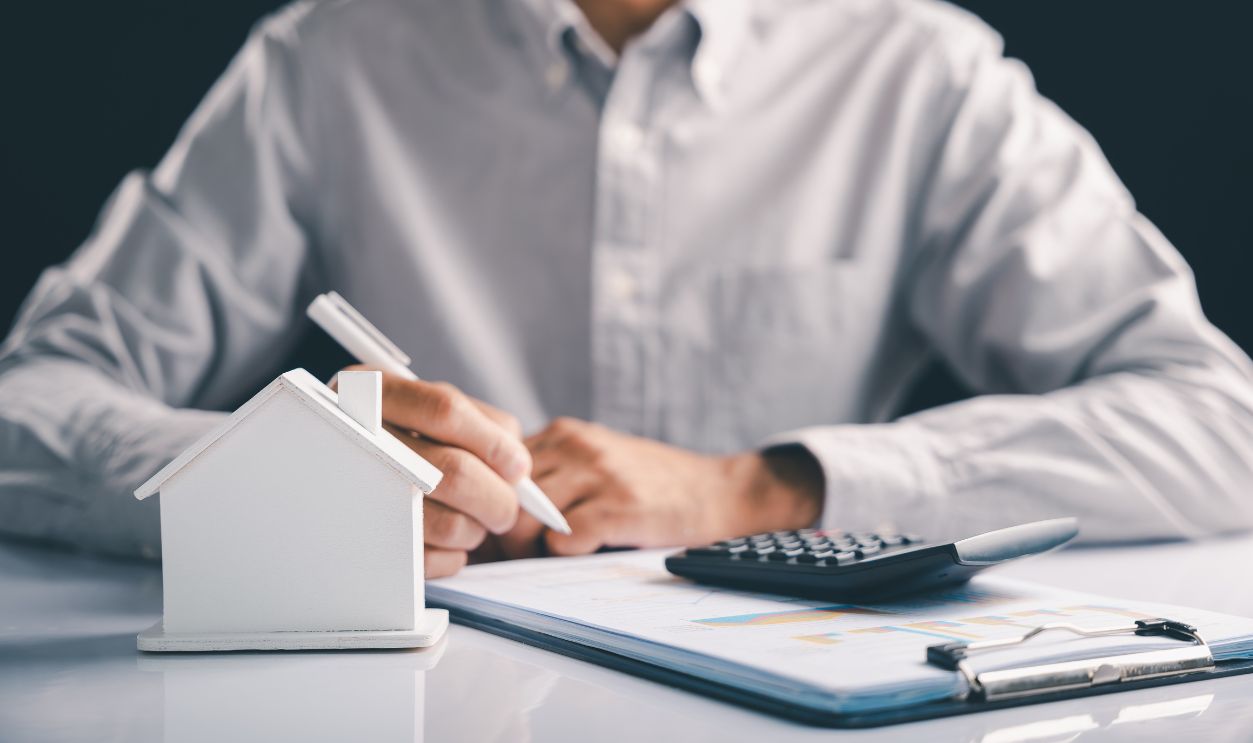 Real estate calculations with a house model on the desk show the costs of property purchase, ideal for illustrating the details of a home loan or investing in real estate and the whole estate process.