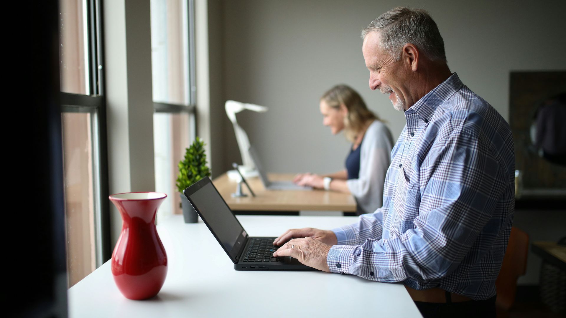 man in blue and white plaid dress shirt using black laptop computer