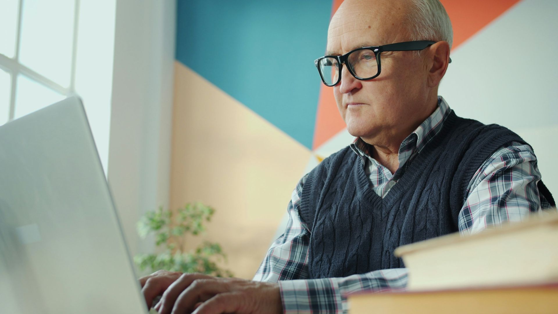 Elderly man with glasses using a laptop