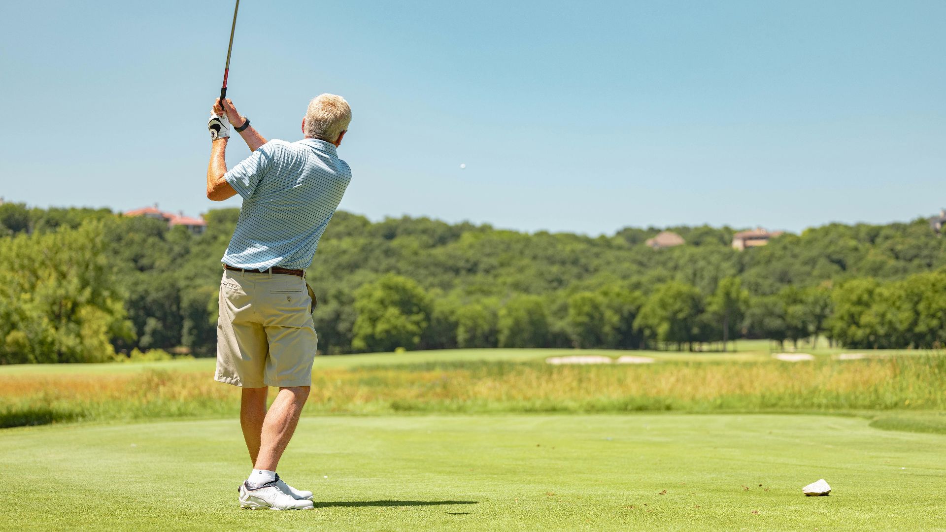 man in white t-shirt and brown shorts playing golf during daytime