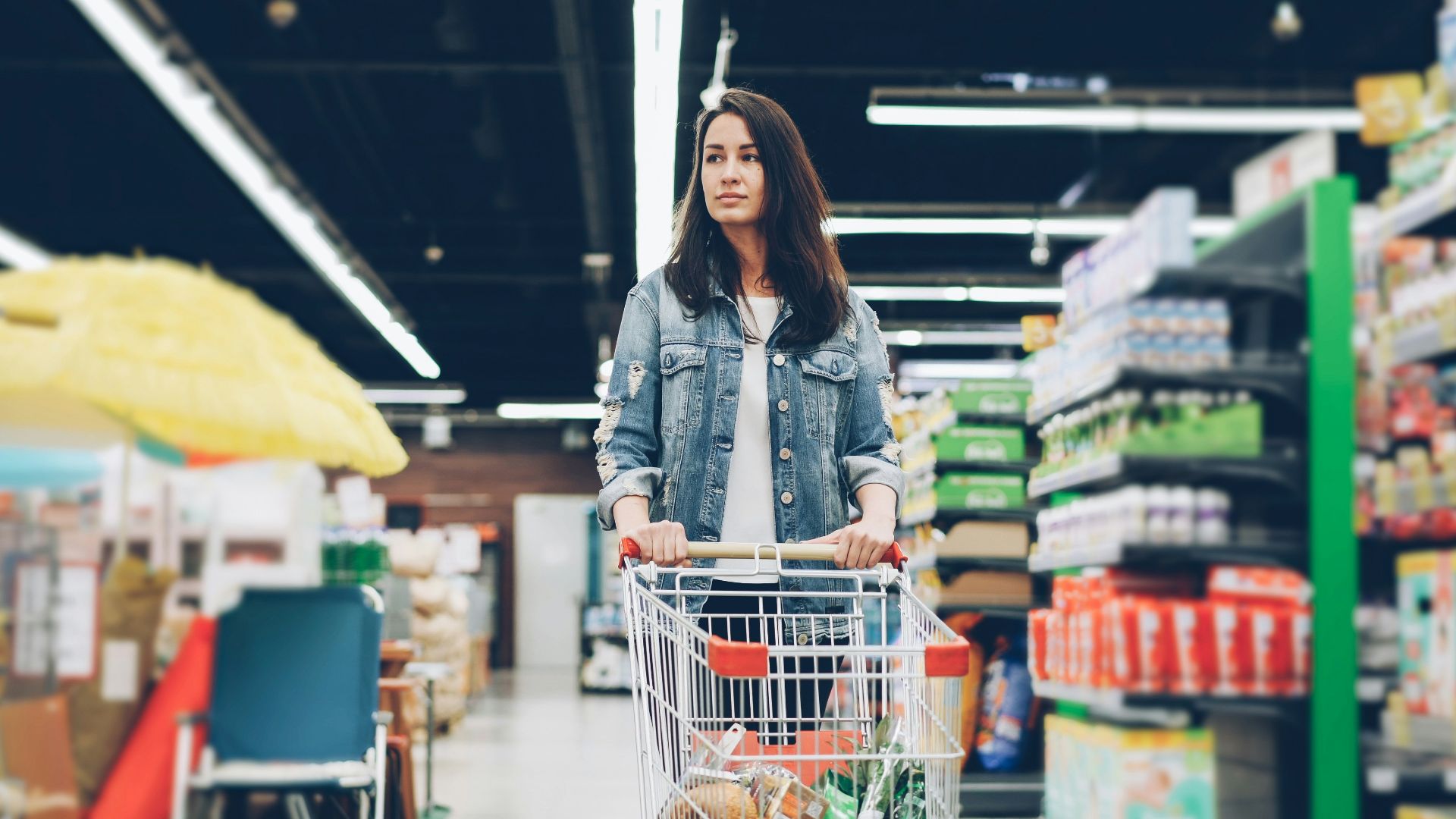 Woman shopping in a grocery store with a cart.