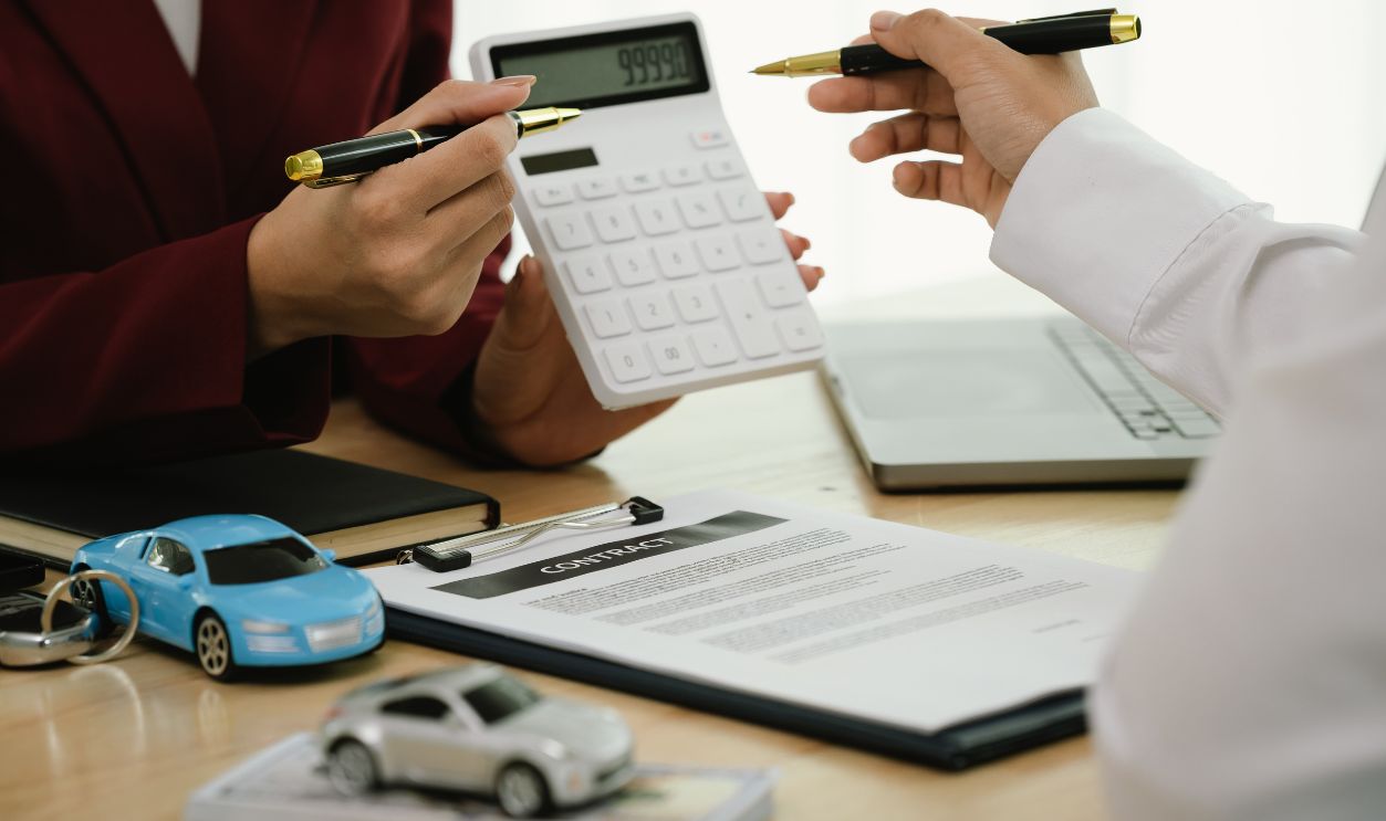 Shutterstock-2666781367, A businessman and client complete an agreement by signing documents for car insurance, loan, or rental, symbolizing finance, contract, policy, investment, purchase, legal paperwork, and secure ownersh