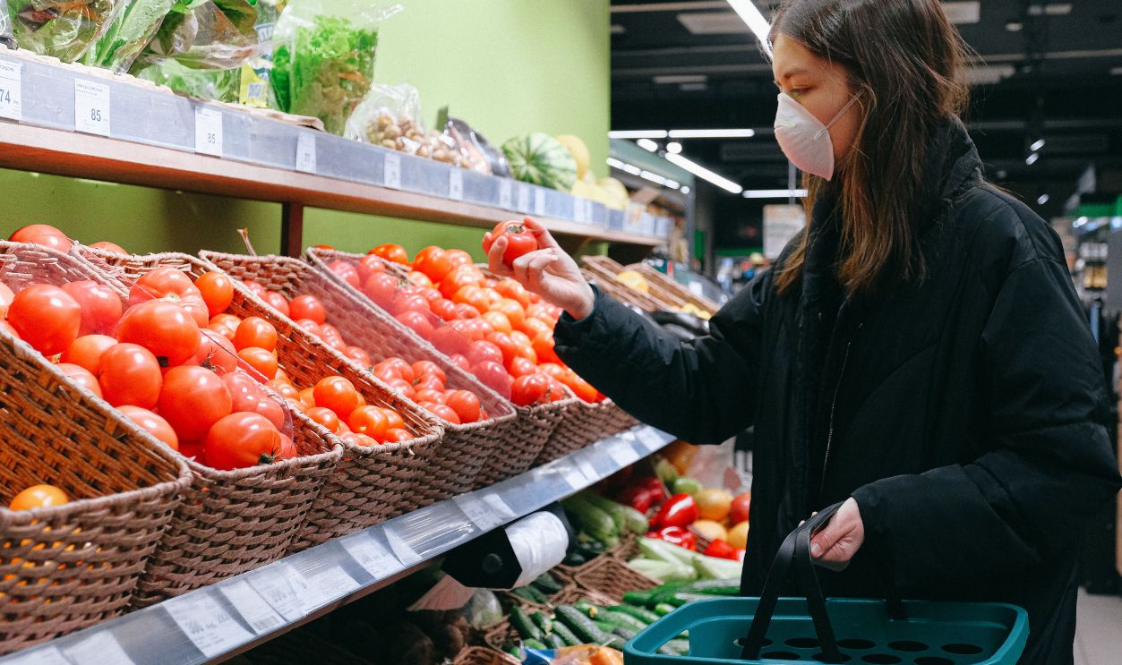 Woman in face mask selecting tomatoes at a grocery