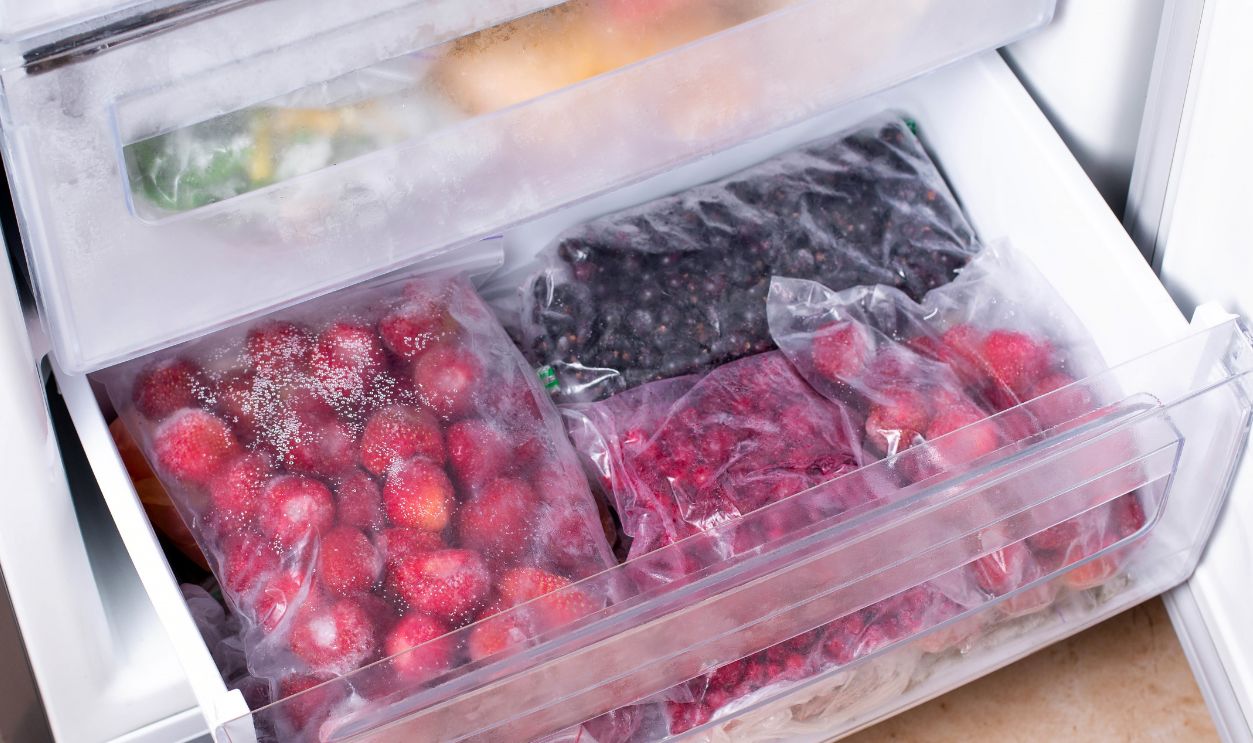 Plastic bags with different frozen berries in refrigerator, horizontal