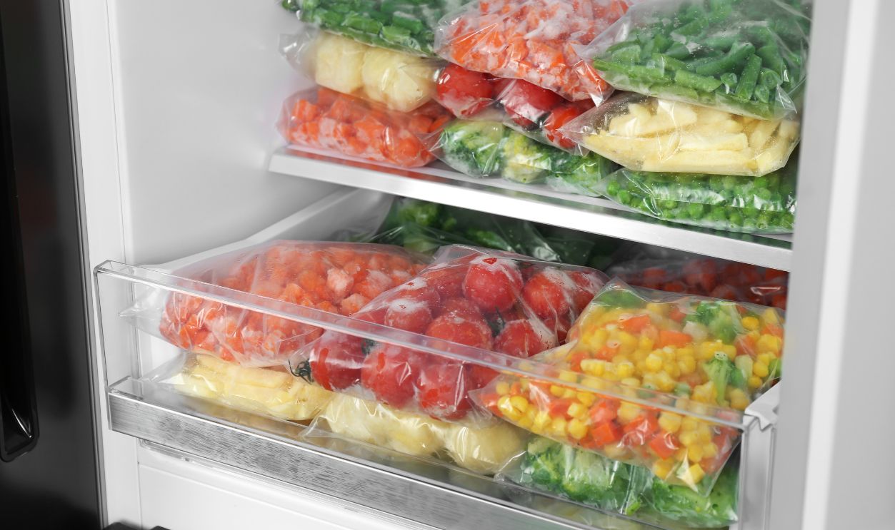 Plastic bags with different frozen vegetables in refrigerator