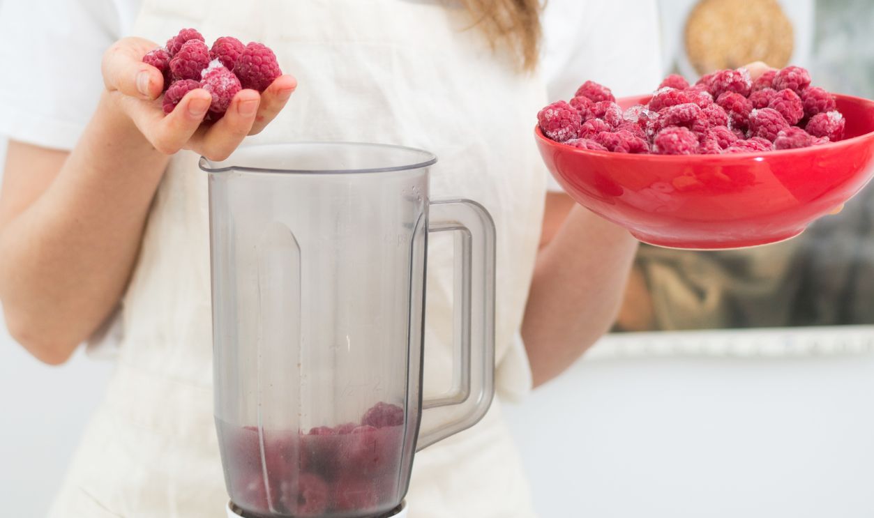 Raspberry Smoothies A woman puts fresh-frozen raspberry berries in a shaker. The concept of healthy eating.