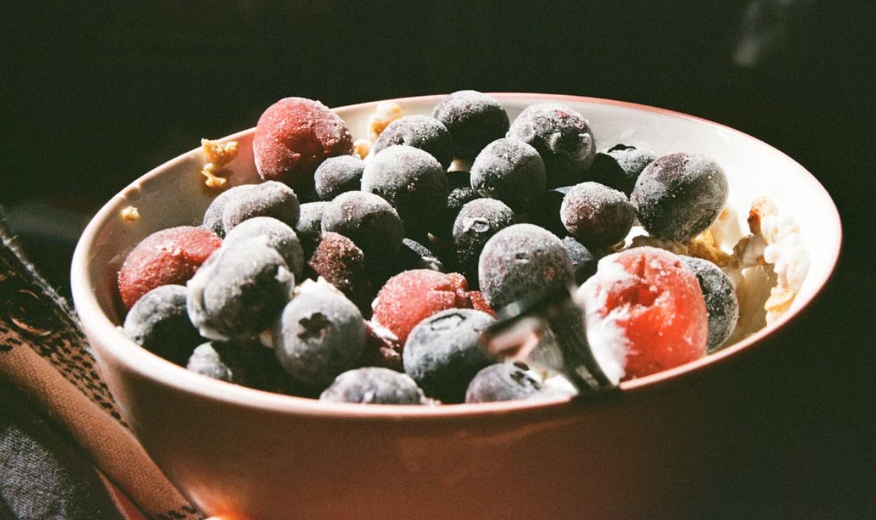 A bowl of frozen blueberries and strawberries capturing morning light