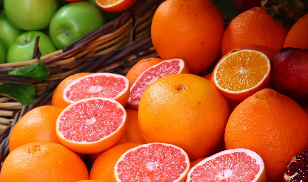 Colorful arrangement of citrus fruits and pomegranates in wicker baskets at a market
