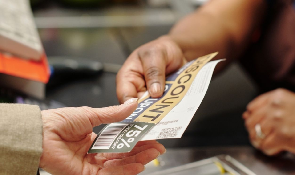 female cashier passing discount coupon and receipt to customer