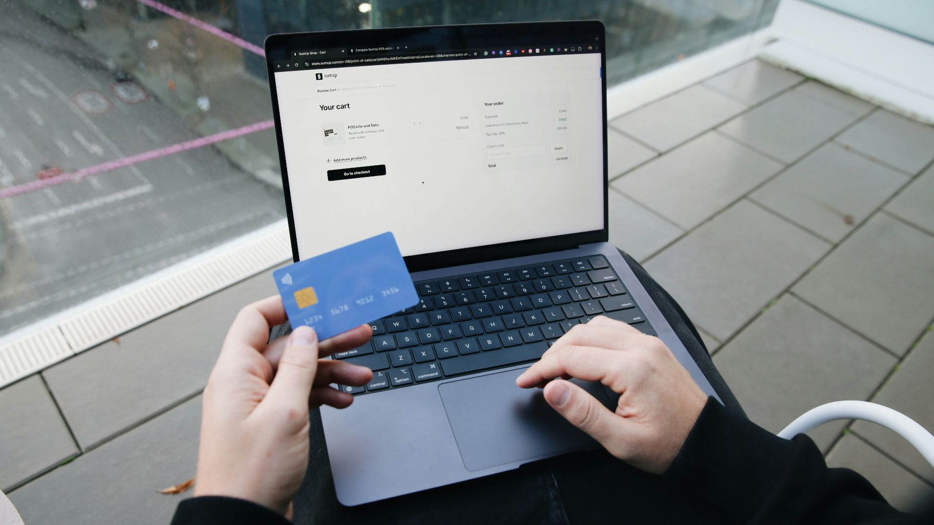 A person sitting in a chair with a laptop and a credit card