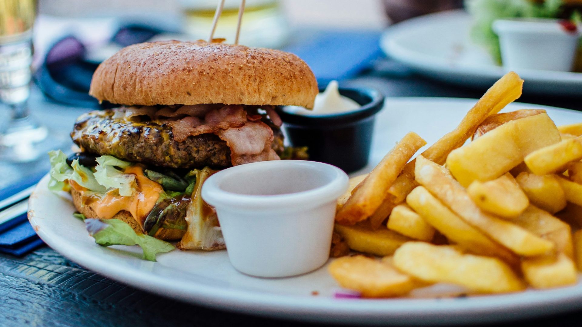 selective focus photography of burger patty, mayonnaise, and French fries served on platter