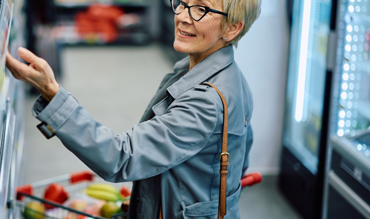 Happy senior woman buying at supermarket. Copy space.