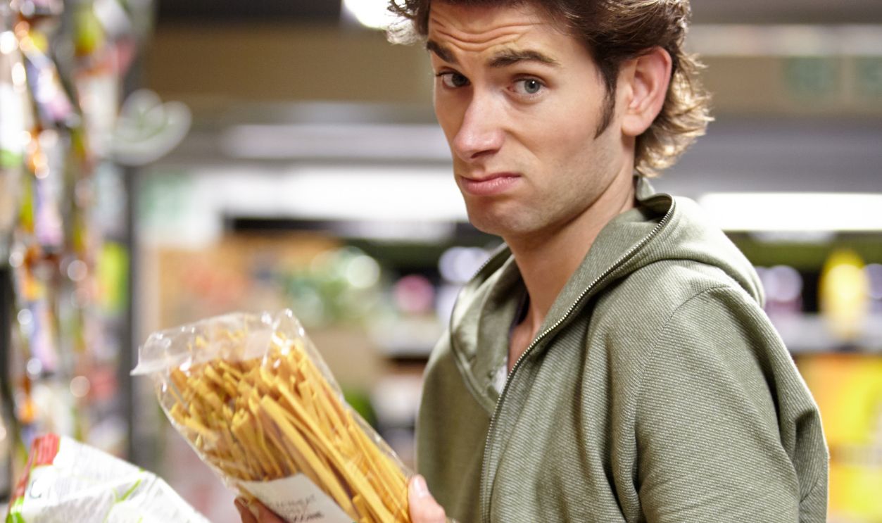 Shutterstock-2376900295, Man, portrait and product comparison in supermarket question, choice or label difference. Male person, thinking and nutrition value for grocery shopping decision, wholesale price or discount search