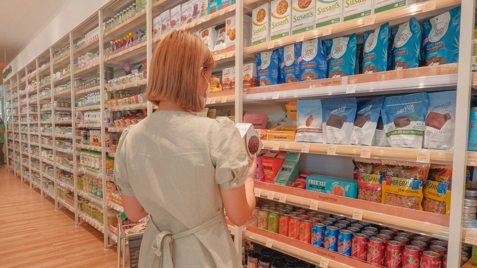 a woman in a white dress is looking at a shelf of food