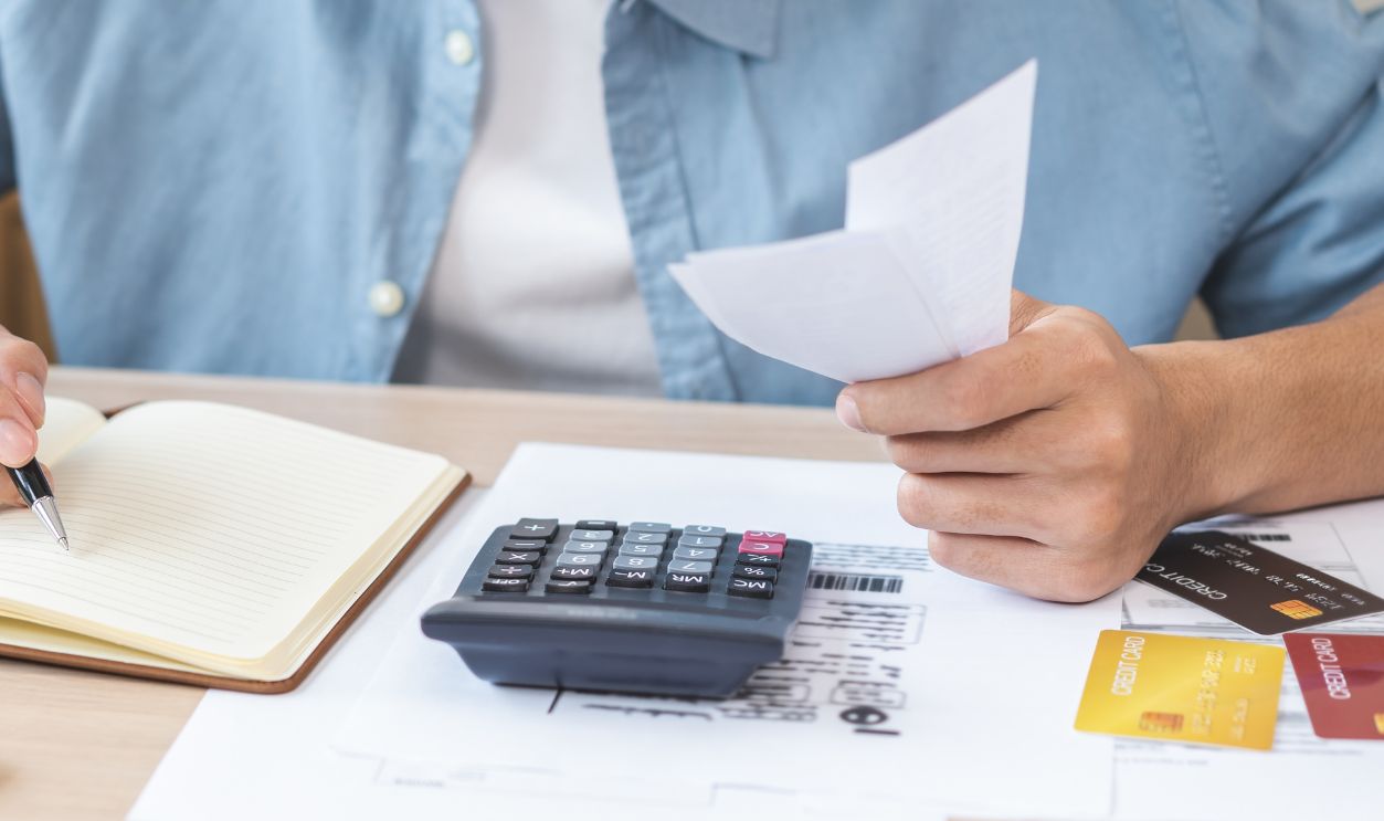 Shutterstock-2673004335, Stressed asian young businessman hand write management budget for saving cost expenses of monthly, male holding bills and receipt for to payment on table at home. Financial, finance of banking concept